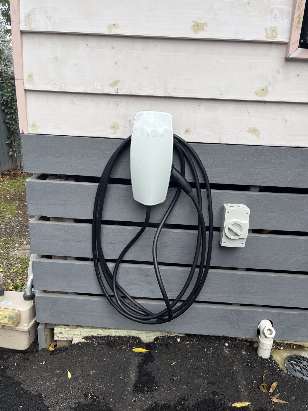 Tesla Wall Connector EV charger installed on exterior weatherboard wall with dedicated isolator