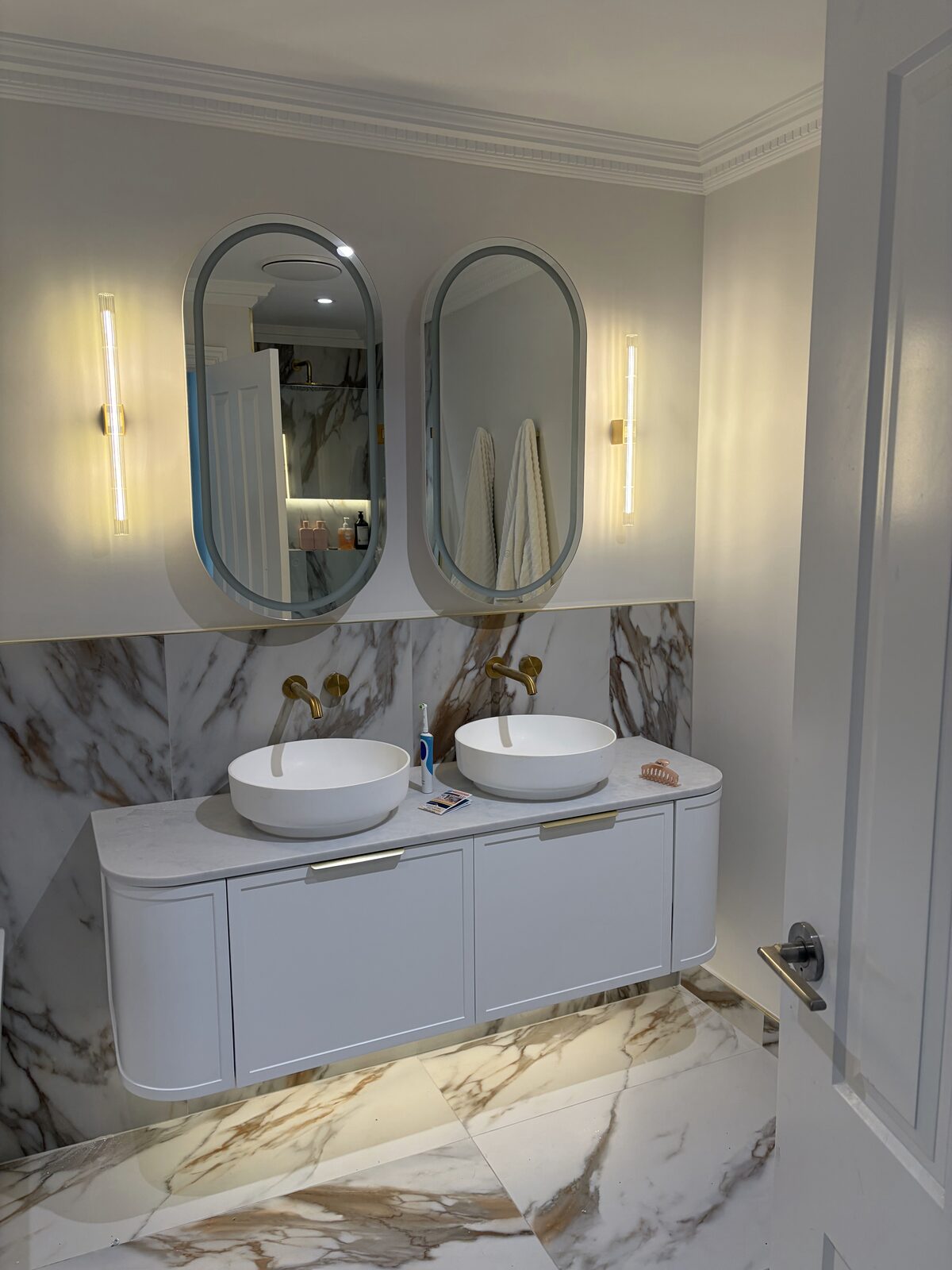 Bathroom renovation with mirror wall lighting and marble finishes