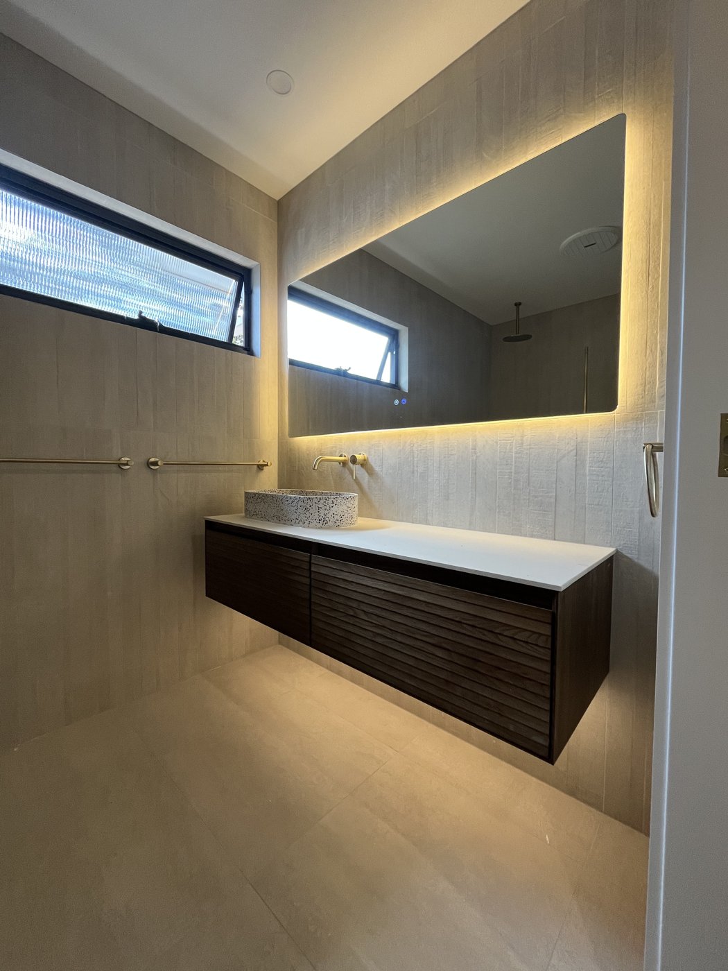 Backlit LED mirror installed above a floating bathroom vanity