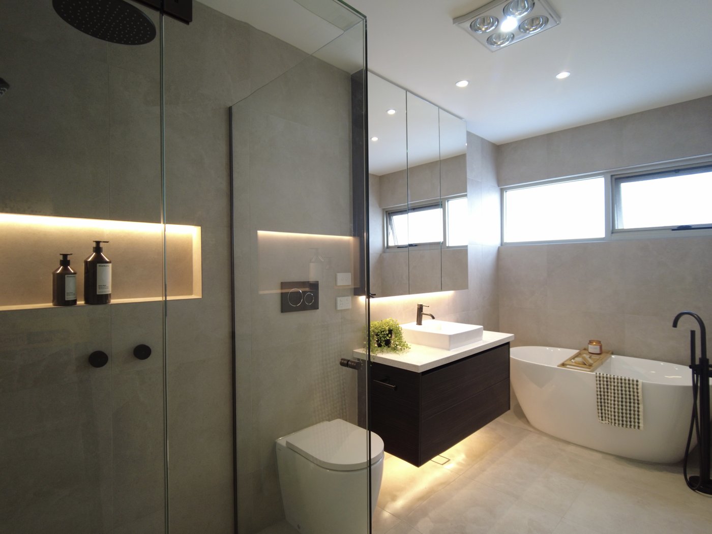 Backlit niche shelving above a freestanding bath in a bathroom renovation