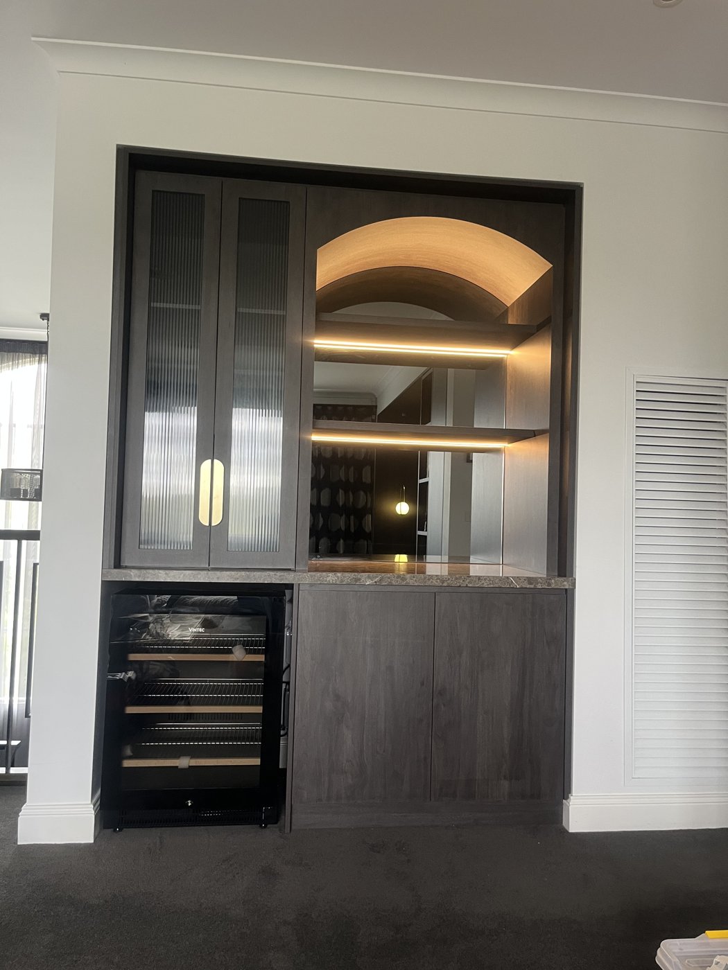 Backlit joinery in a bar cabinet with arched shelving