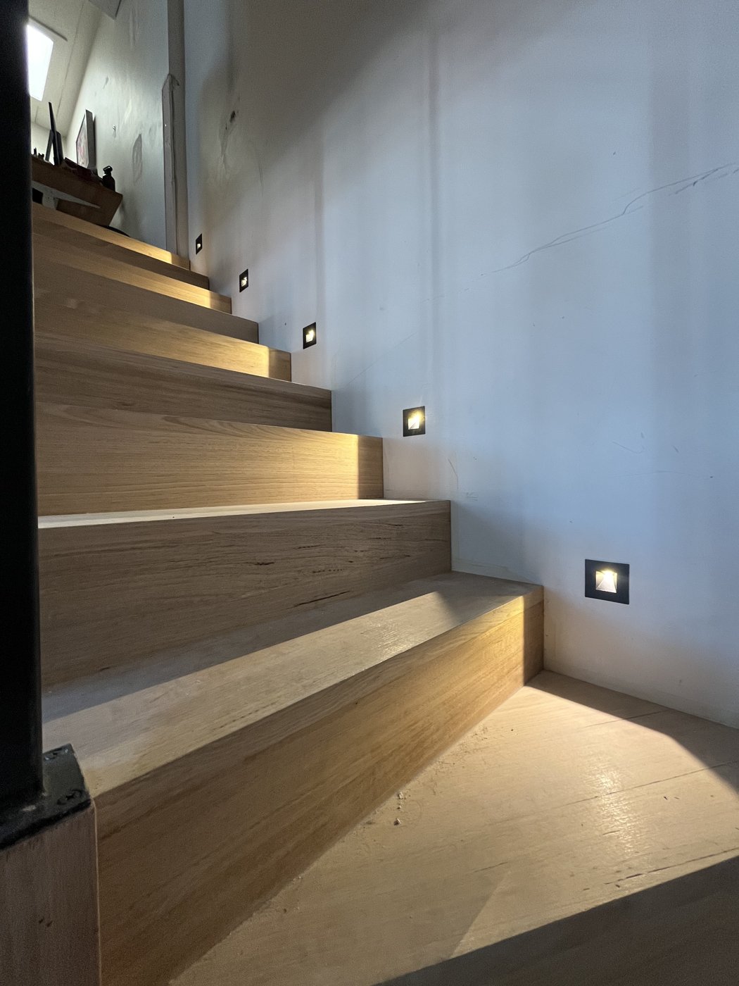 Recessed LED step lights installed along a timber staircase, wide view