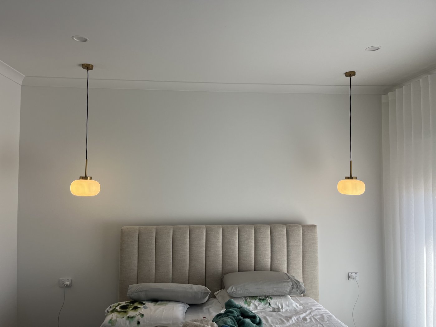 Twin pendant lights installed either side of a bed