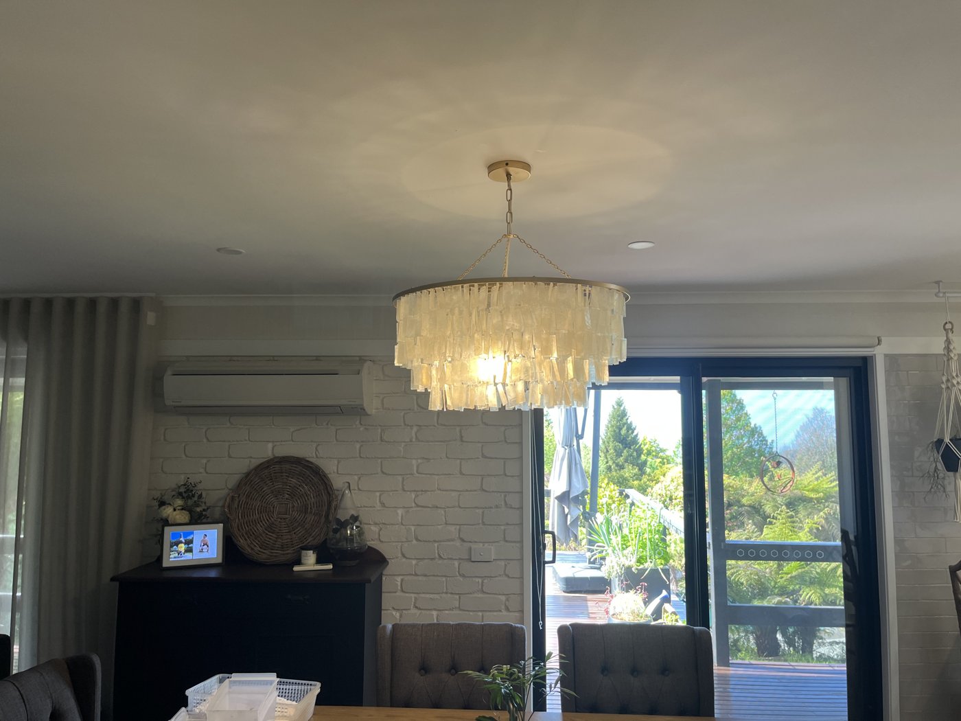 Tiered capiz shell pendant chandelier installed above a dining table