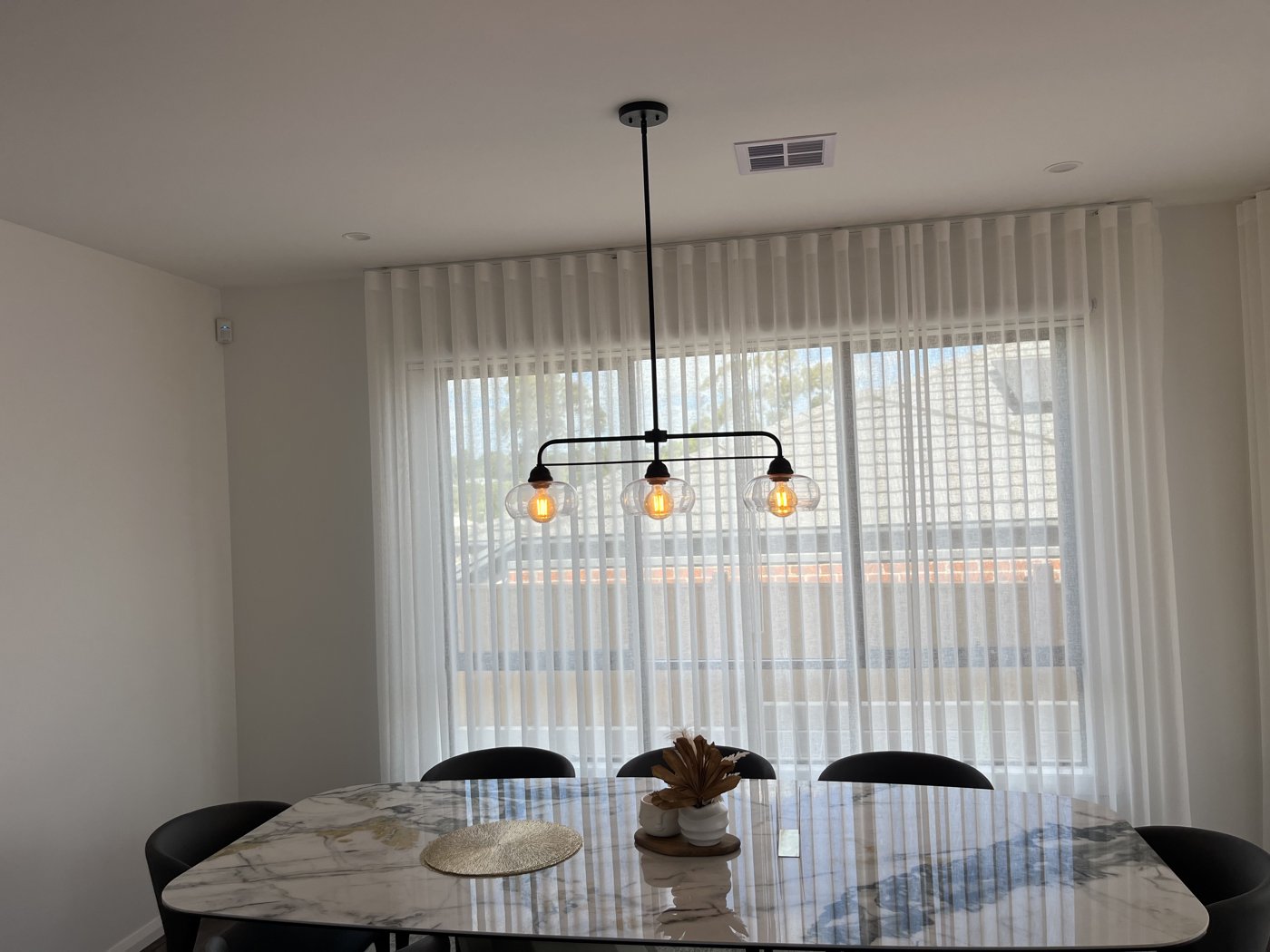 Black cluster pendant light installed above a dining table