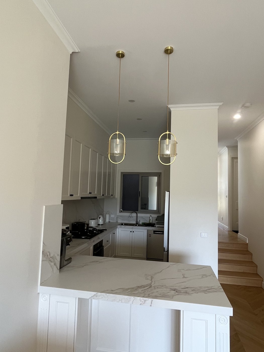 Twin pendant lights installed above a marble kitchen island