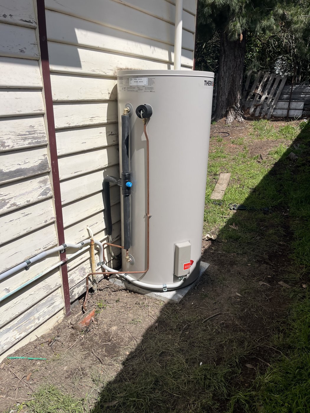 Electric hot water unit with dedicated circuit and isolator installed against an exterior wall