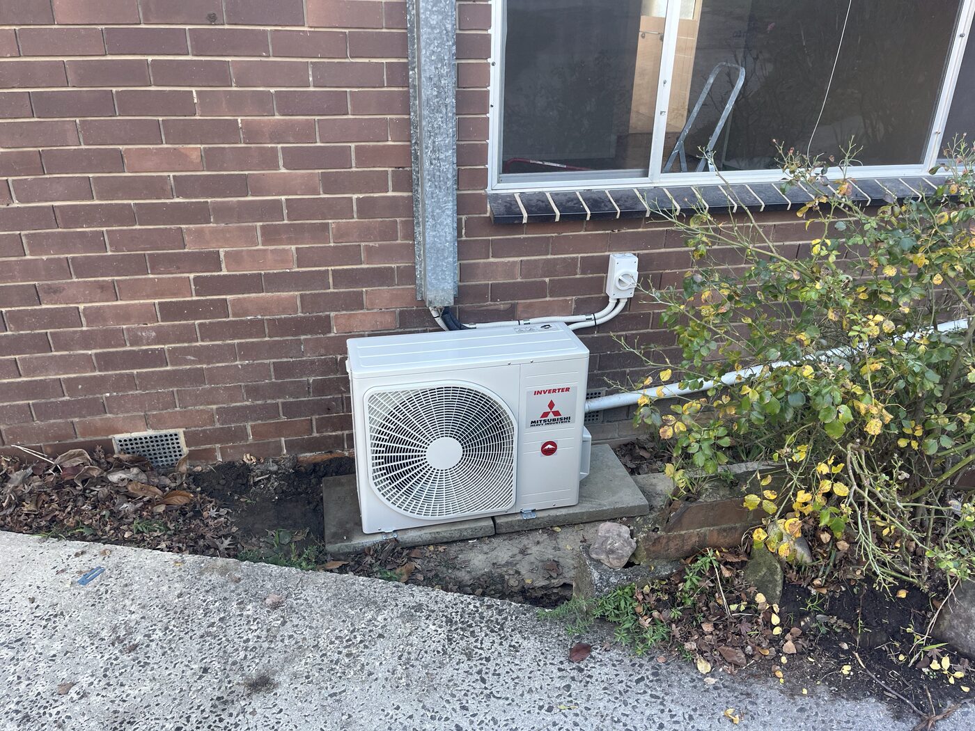 Split system outdoor condenser unit mounted on a brick wall