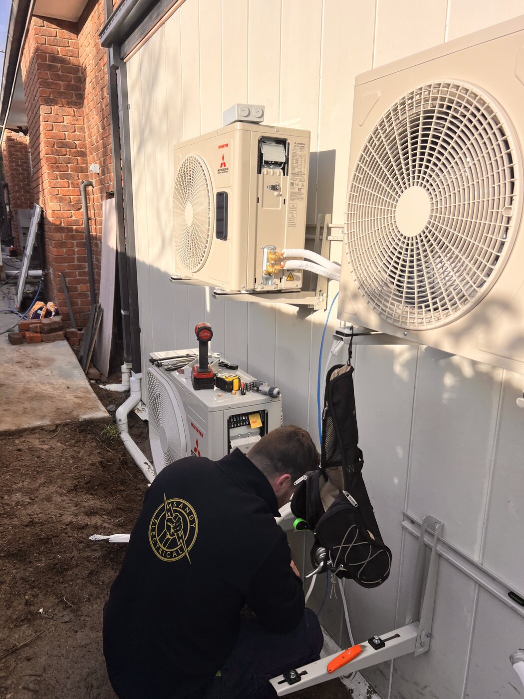 Sandy Electrical technician installing Mitsubishi split system outdoor units