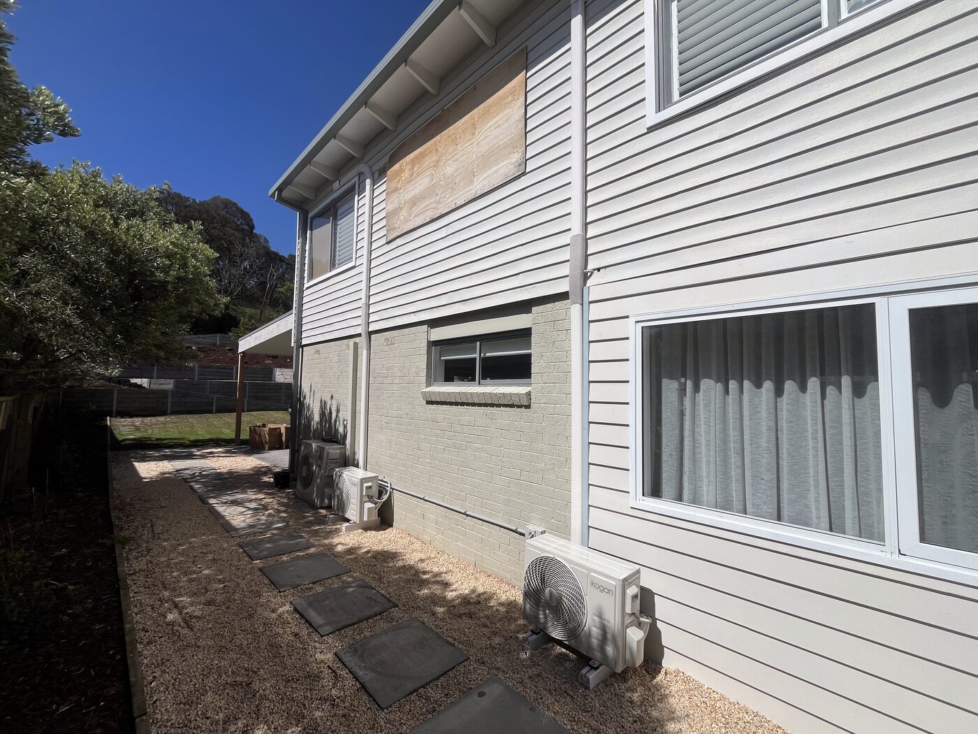 Two split system outdoor condenser units installed on a weatherboard home
