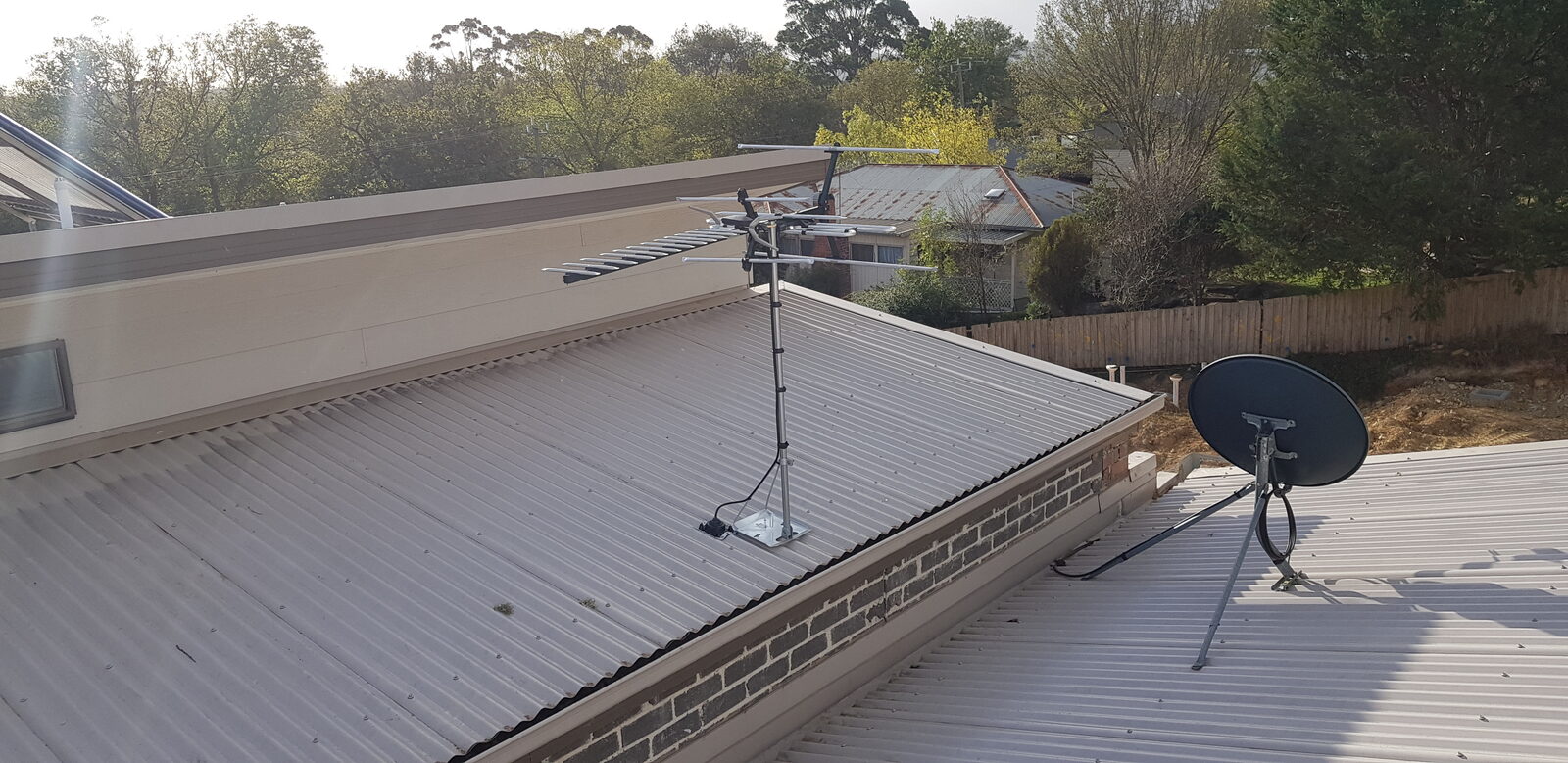 TV antenna and satellite dish installed on a tiled roof