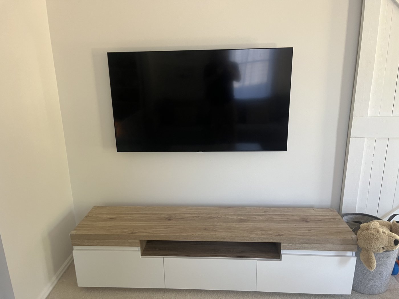 TV wall mounted above a floating timber TV unit with no visible cables