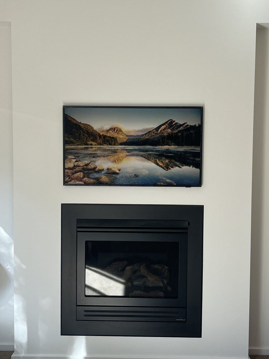 Samsung Frame TV wall mounted above a gas fireplace in art mode