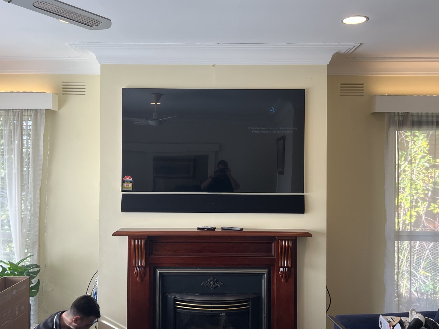 TV wall mounted above a timber mantel fireplace with sound bar and no visible cables